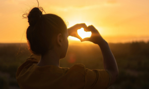 woman makes a heart sign with her hands