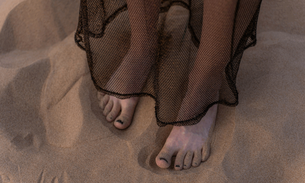woman is grounding herself with her feet in the sand