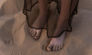woman is grounding herself with her feet in the sand
