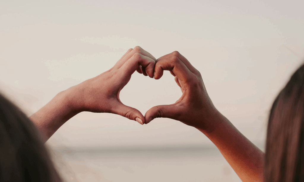 two hands in the air making a heart shape showing self compassion