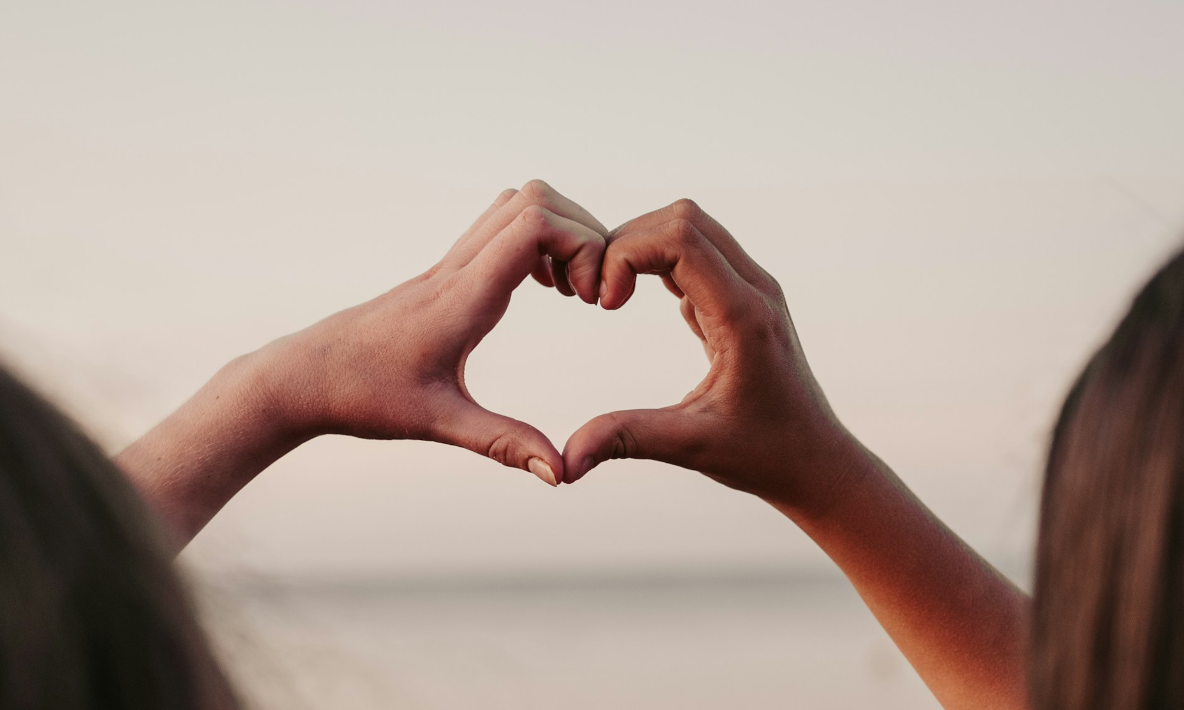 two hands in the air making a heart shape showing self compassion