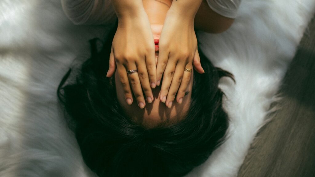 woman feels shame and hides herself behind her hands