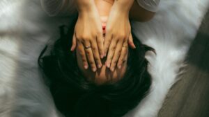 woman feels shame and hides herself behind her hands